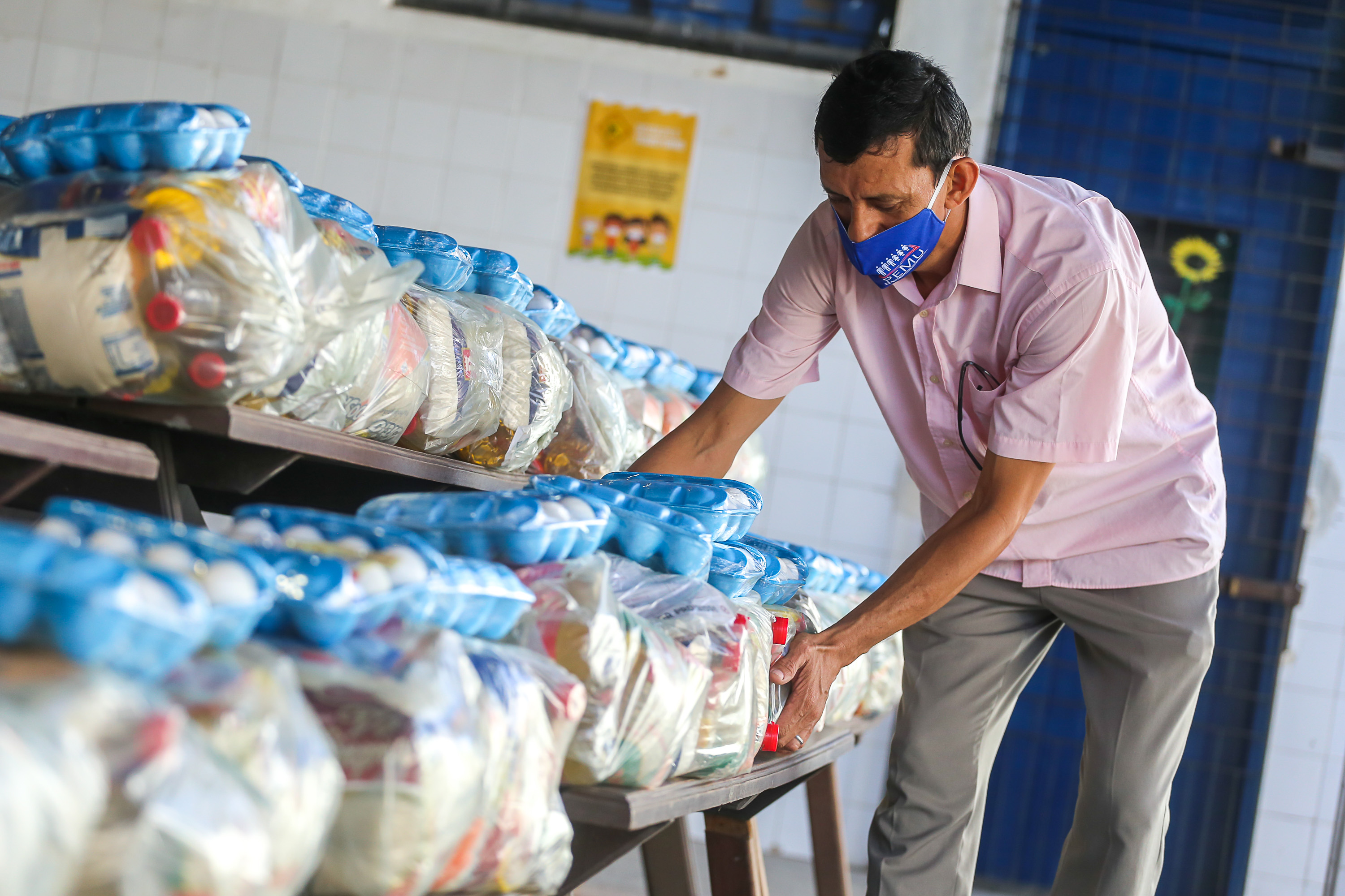 homem de máscara pegando kit de alimentação em cima de mesa com vários expostos